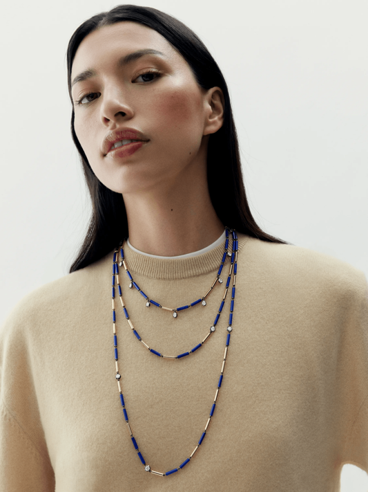 Model wearing layered long necklace featuring blue lapis beads and small diamonds set in alternating segments, showcasing artisanal craftsmanship and contemporary design. View 3