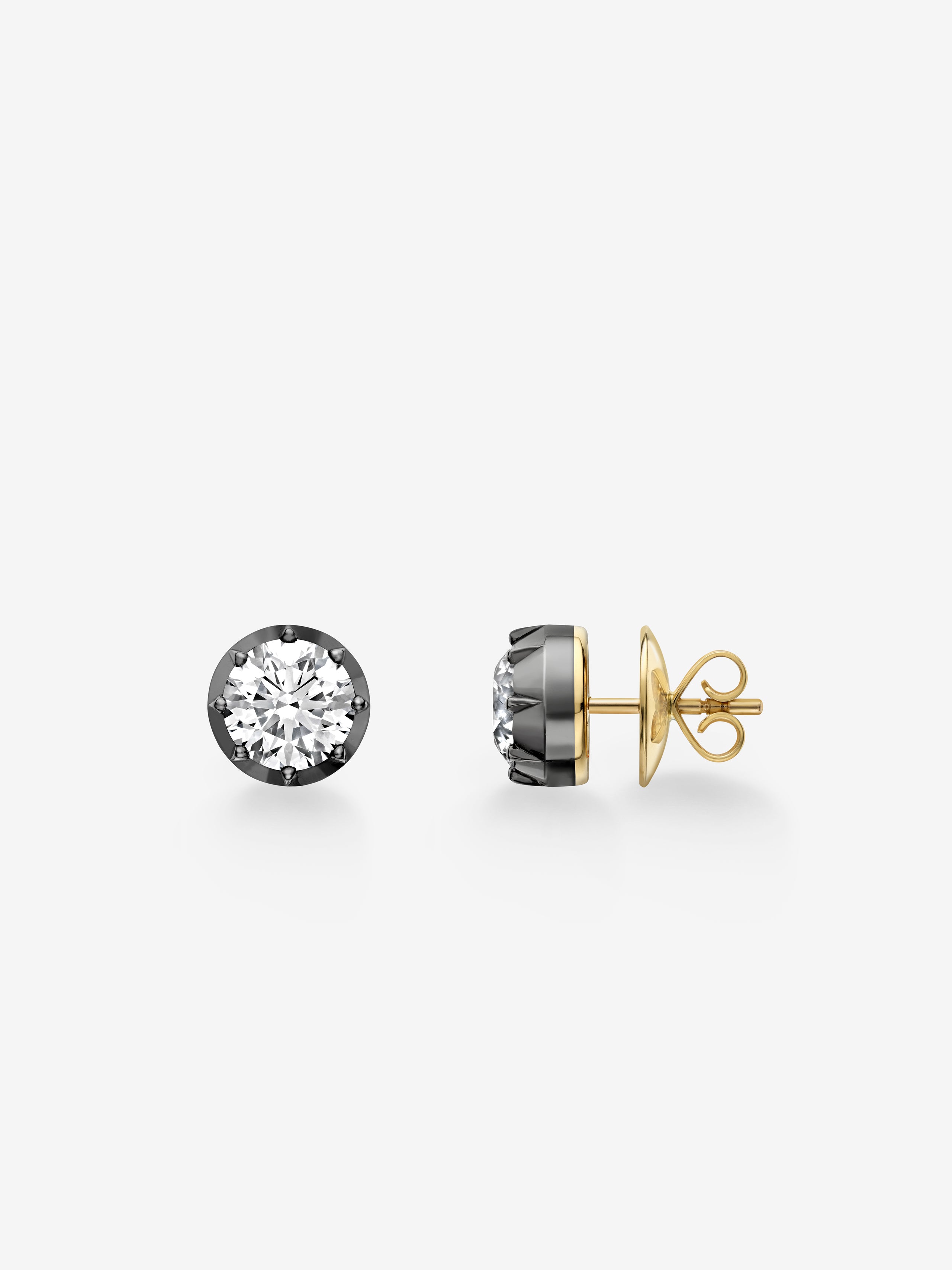 Pair of contemporary stud earrings featuring round diamonds set in blackened gold with traditional yellow gold posts and butterfly backs. View 2