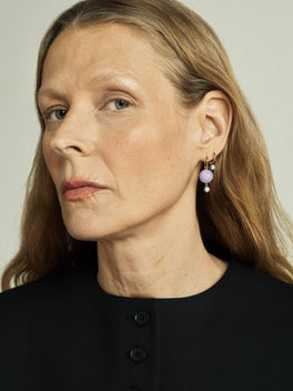 Close-up of a woman wearing hoop earrings featuring lilac jade and a 0.40ct diamond sphere, showcasing a blend of antique-inspired and contemporary design.