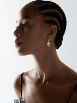 Profile of a woman wearing a pear-shaped diamond hoop earring with a delicate gold setting, showcasing a contemporary and antique-inspired design.