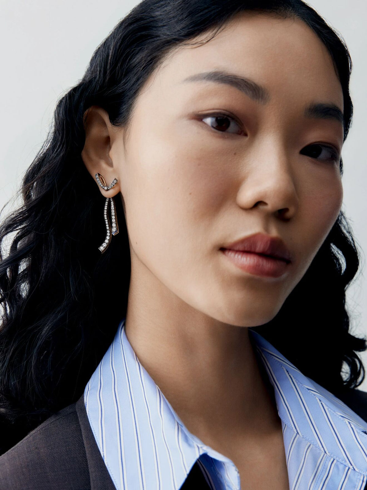 Close up portrait of a model wearing diamond bow and ribbon drop earrings in a contemporary design by Jessica McCormack View 5