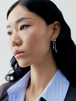 Close up portrait of a model wearing diamond bow and ribbon drop earrings with delicate cascading strands in a contemporary design