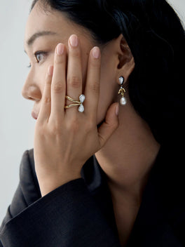 Close-up of a model wearing a pear shaped diamond and white gold ring with diamond drop earrings, showcasing Jessica McCormack jewellery.