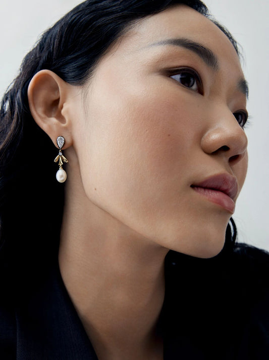 Close-up portrait of a model wearing a diamond and gold bow earring with a pearl drop, showcasing contemporary jewellery craftsmanship View 3