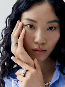 Close up portrait of a woman wearing a pearl and diamond ring with bow inspired shoulders, showcasing contemporary jewellery craftsmanship