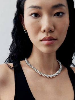 Jessica McCormack diamond ribbon necklace in white gold, styled on a model in a black dress with an intricate bow inspired design
