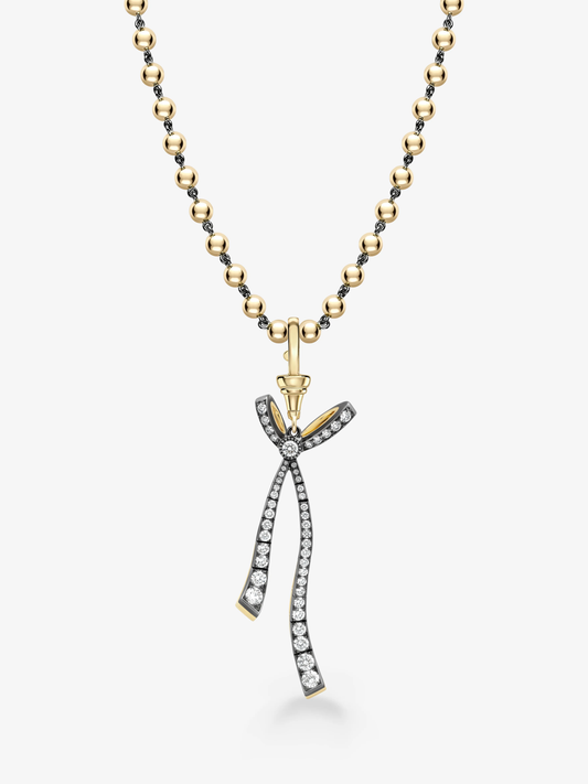 Jessica McCormack diamond bow pendant with flowing ribbon tails on a blackened gold and yellow gold Ball n Chain necklace View 2