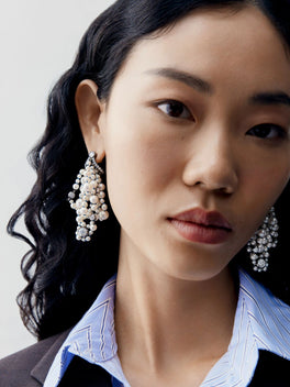 Jessica McCormack diamond and pearl clustered earrings worn by a model in a contemporary layered look