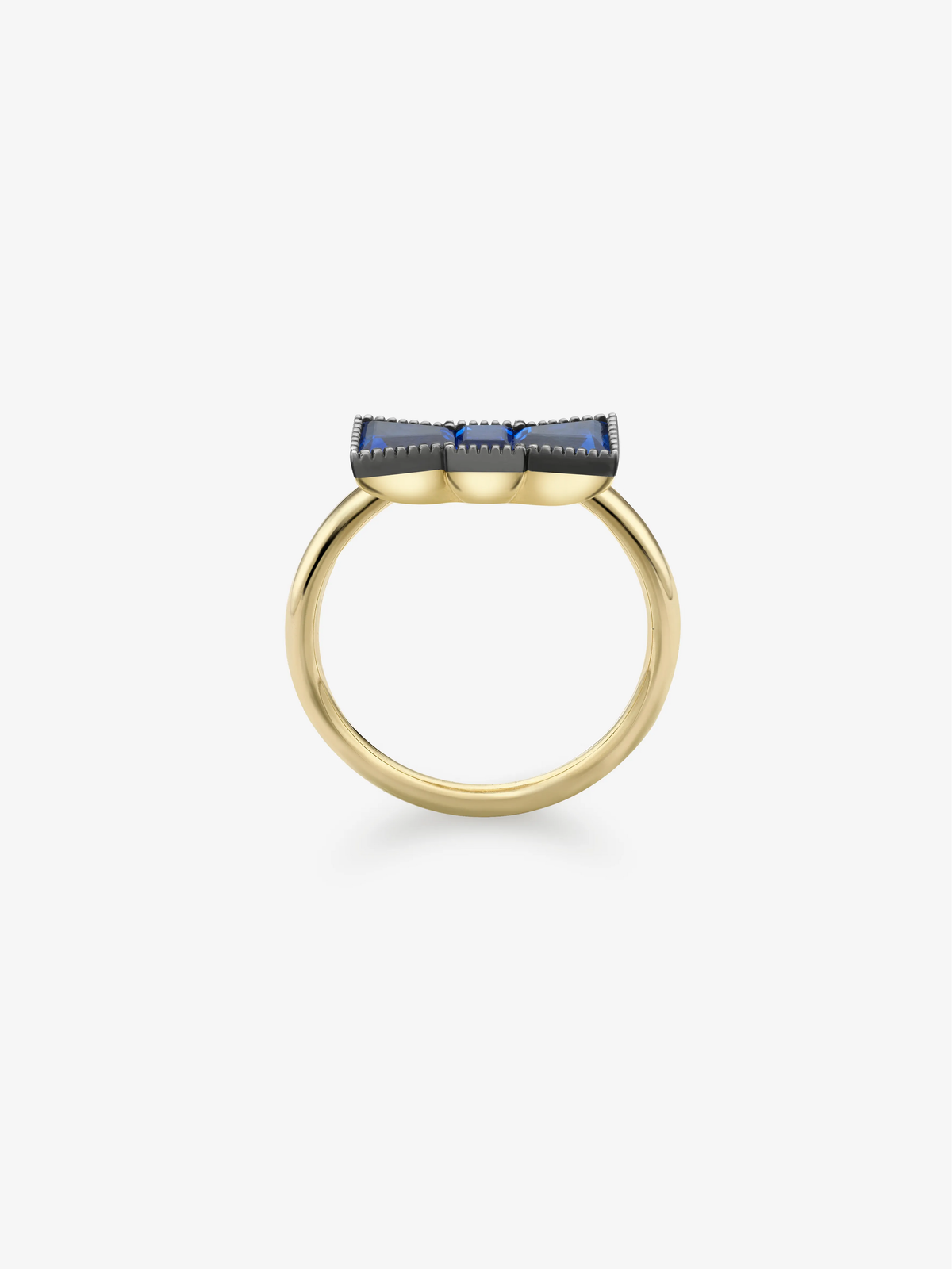 Sapphire ring with a yellow gold band and blue sapphire bow detail, shown in profile on a white background View 4