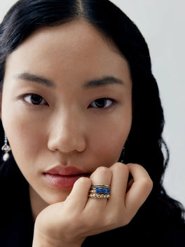 Close up portrait of a woman wearing a blue sapphire ring with textured gold bands, showcasing contemporary jewellery and distinctive craftsmanship