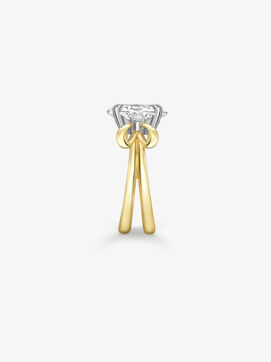Oval cut diamond ring with a white gold setting and sculptural yellow gold bow inspired shoulders against a white background View 4
