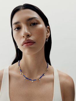 Woman wearing a blue beaded necklace against a plain background