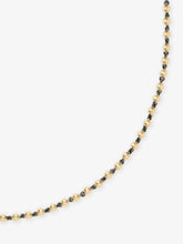 Close-up of a delicate yellow gold ball chain necklace with dark oxidized links, showcasing a blend of antique-inspired craftsmanship and contemporary design.