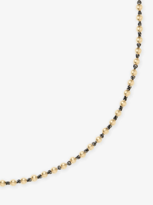 Close-up of a delicate yellow gold ball chain necklace with dark oxidized links, showcasing a blend of antique-inspired craftsmanship and contemporary design. View 2