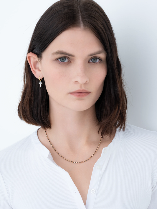 Close-up of a woman wearing a delicate rose gold micro ball necklace with a subtle matte finish, paired with minimalist diamond earrings, showcasing timeless craftsmanship and contemporary elegance. View 3