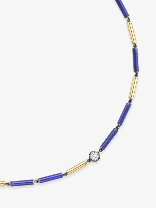 Close-up of a handcrafted necklace featuring alternating deep blue lapis cylinders and slender gold tubes with a single bezel-set round diamond, showcasing antique-inspired craftsmanship. View 2