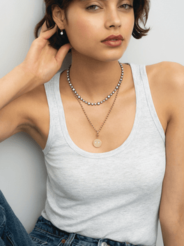Model wearing a round happy face pendant necklace layered with a diamond necklace, showcasing playful contemporary jewellery styling by Jessica McCormack
